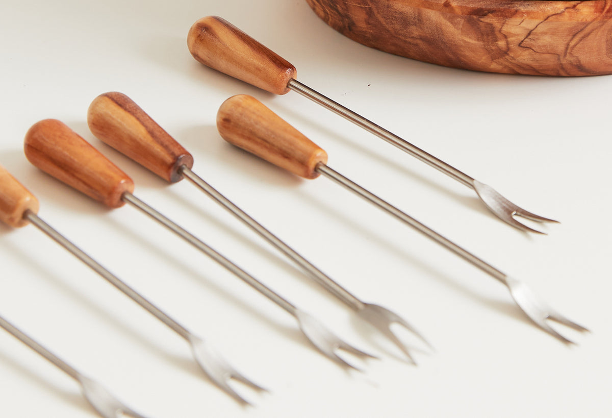 Five appetizer forks with olivewood handles and metal tines arranged in a row.