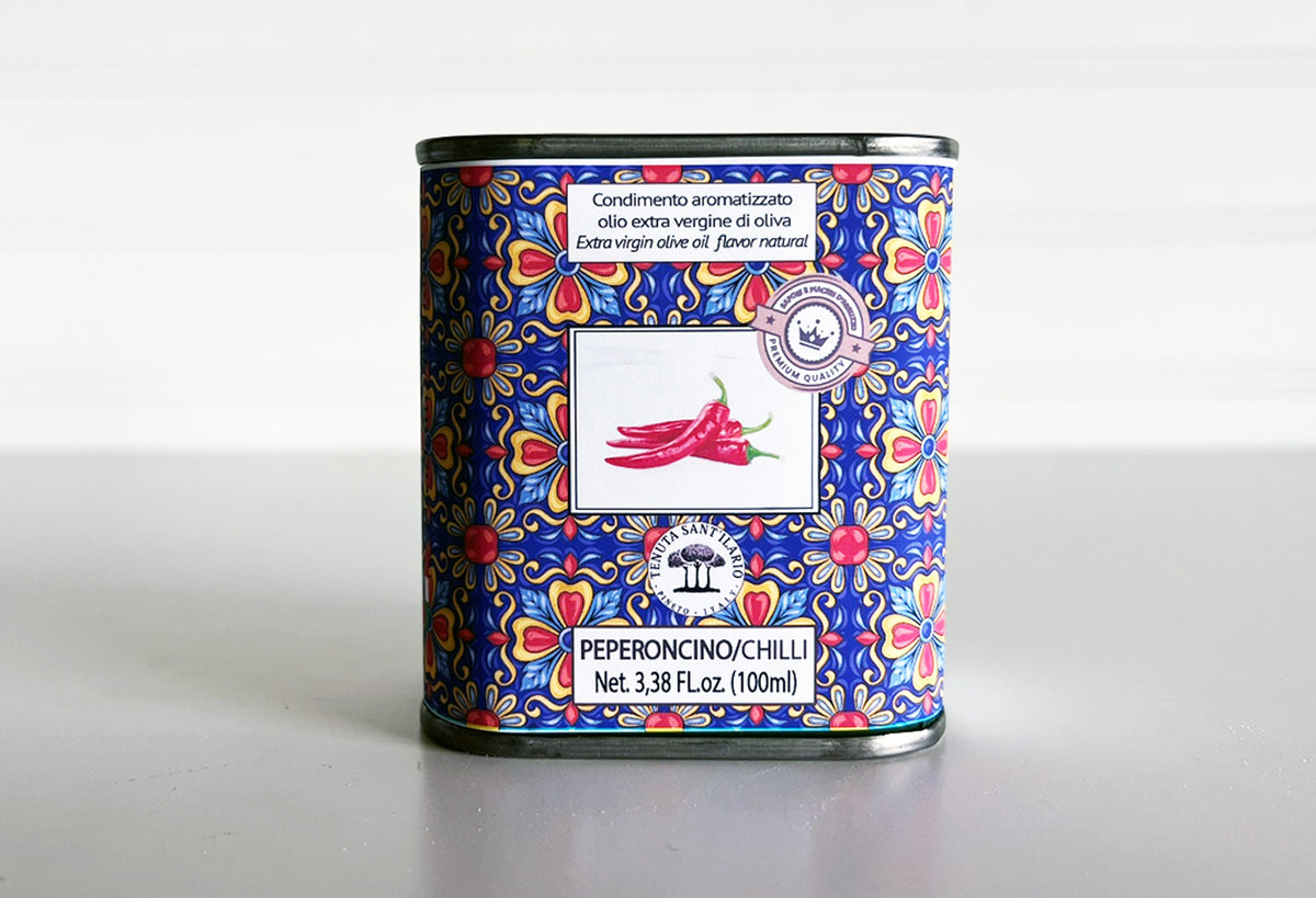 Cylindrical tin with blue and red floral pattern containing peperoncini chilli infused olive oil, 100ml.