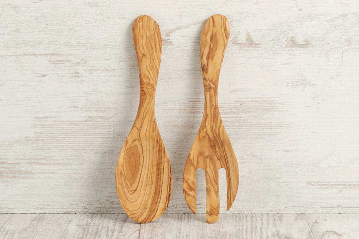 Pair of wooden salad servers with oval spoon and fork ends, carved from light natural wood with visible grain patterns.