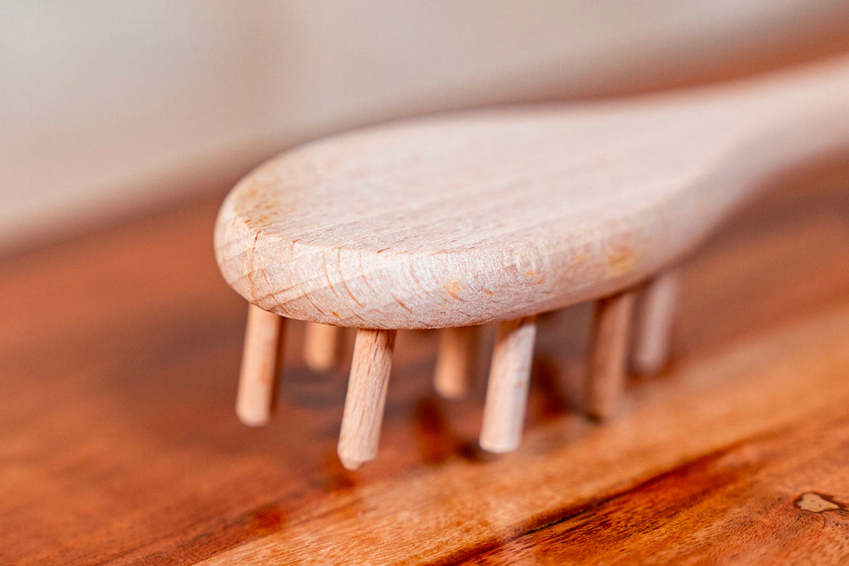 Light wood spaghetti fork with rounded handle and four short prongs, resting on a wooden surface.