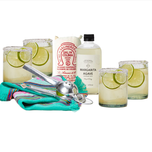 Four margarita cocktails with lime slices, agave syrup bottle, sal de colima, bar spoon, and colorful striped cloth.