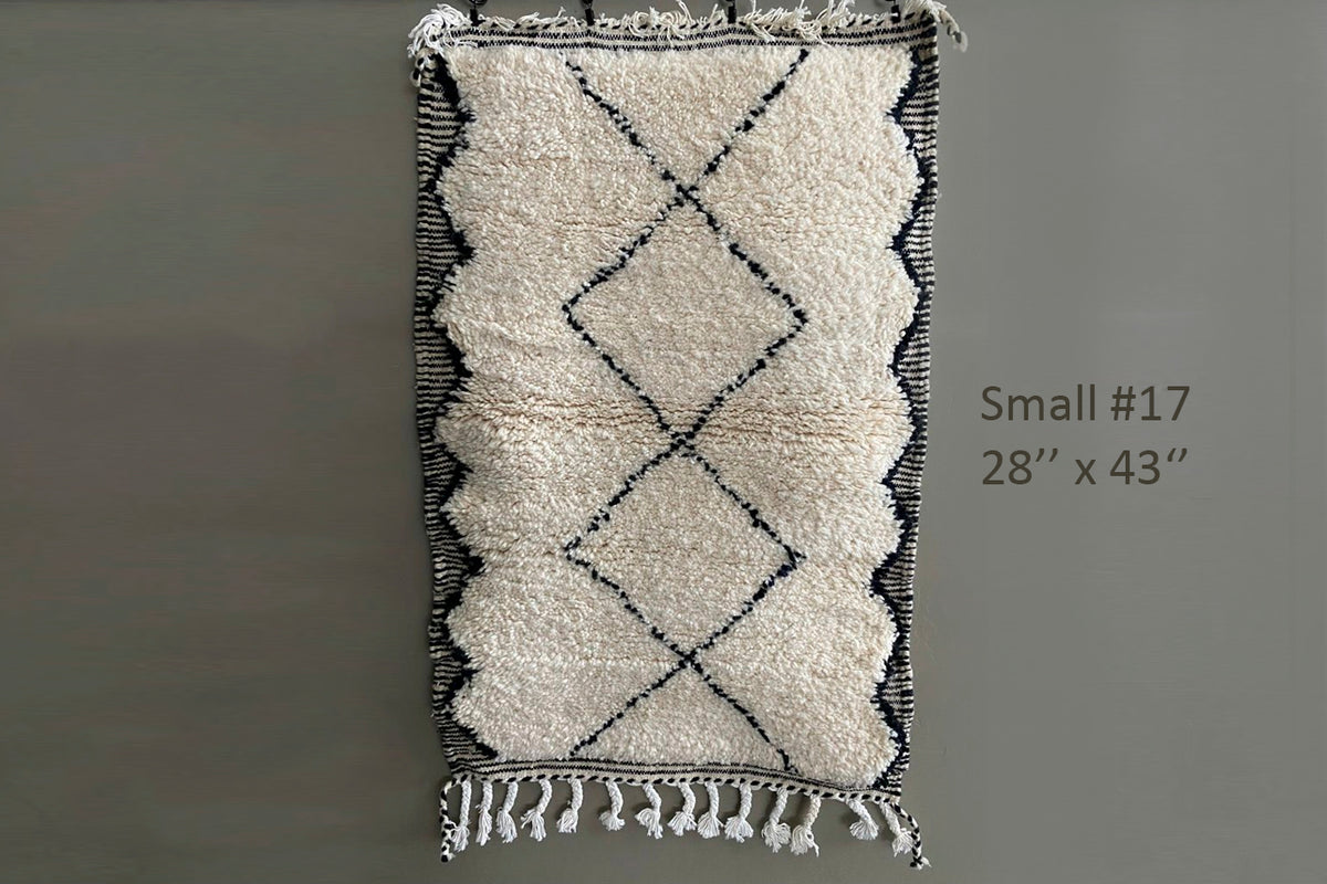 Cream wool rug with black diamond pattern and fringe edges, 28" x 43".