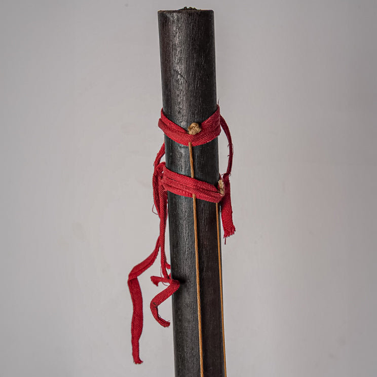 Dark wooden cylindrical neck with red fabric binding and brass details.