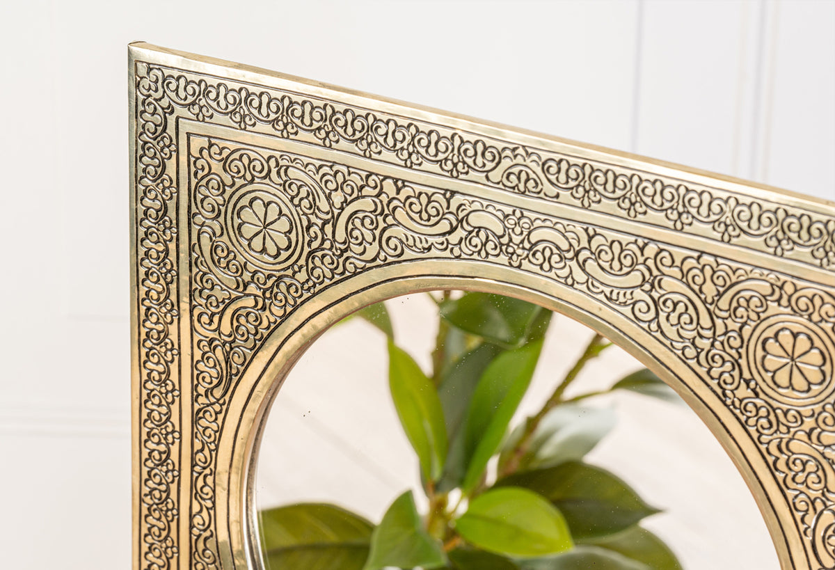 Round mirror with ornate gold-toned frame featuring intricate geometric and floral patterns throughout the border.