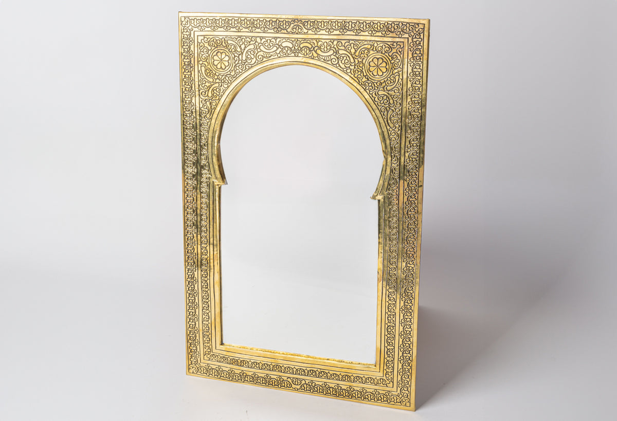 Gold-toned rectangular mirror with ornate carved frame featuring geometric and floral Islamic patterns and arched opening.