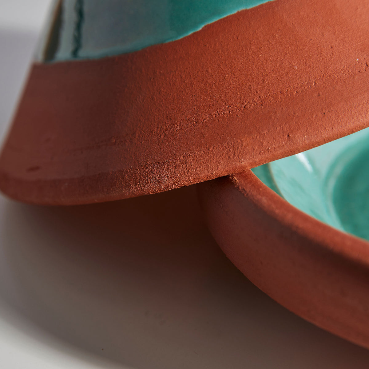Terra cotta tagine with turquoise interior lid, showing rounded base and cone-shaped top with textured surface.