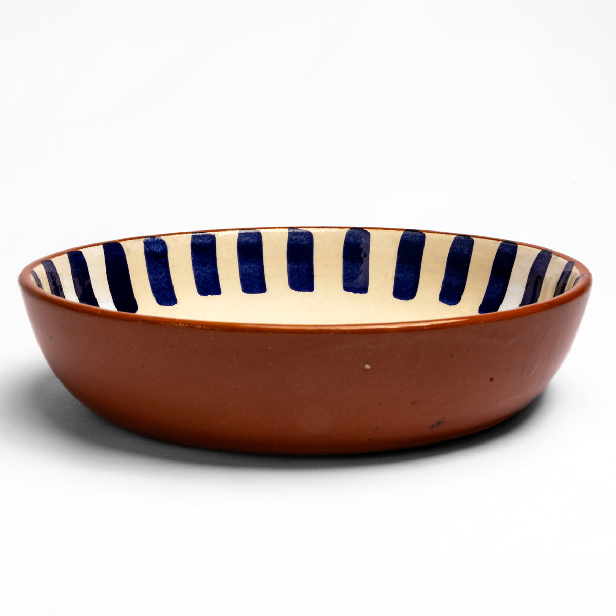 Terracotta bowl with cream interior featuring navy blue vertical stripes and geometric patterns around the rim.