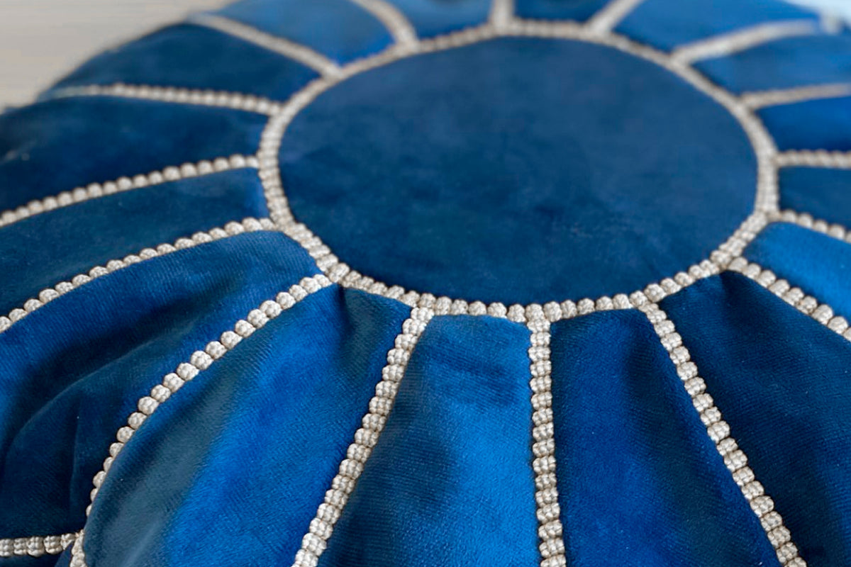 Blue poufs with white beaded geometric circular patterns and stitched details.