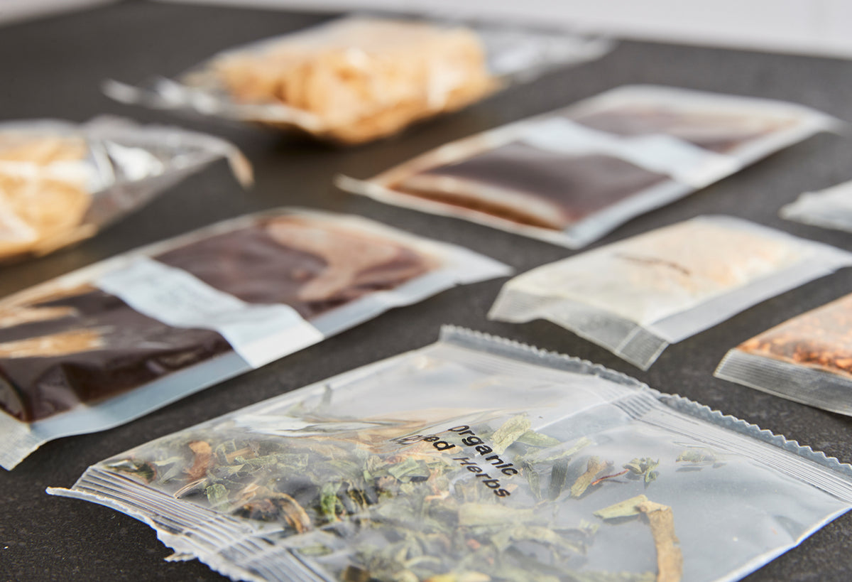 Multiple ingredient packets and crackers arranged on dark surface for Thai cooking bundle.