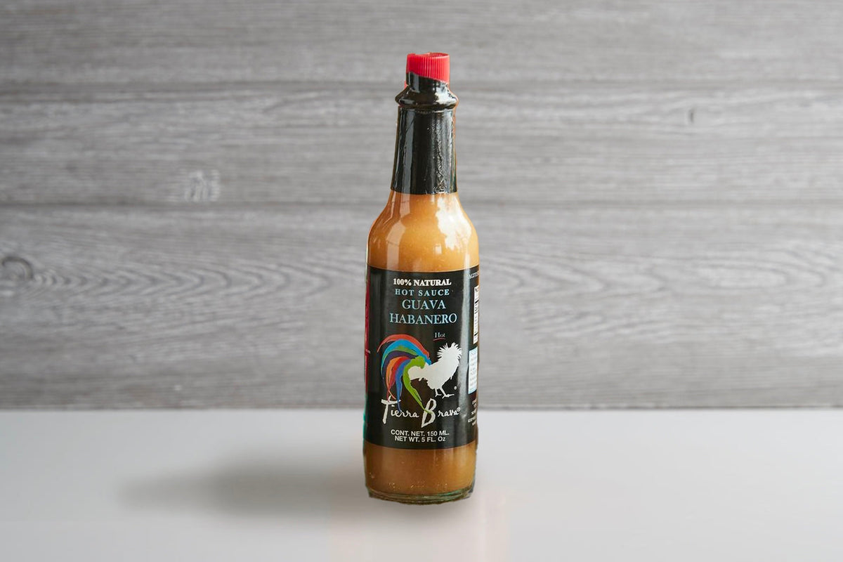 Tierra Brava habanero hot sauce bottle with red cap, black and tan label, and orange-brown sauce visible inside.