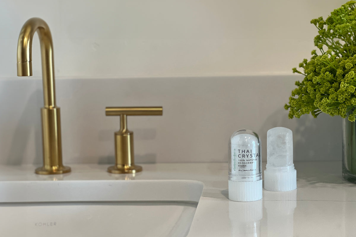 Two white crystal deodorant stones with ribbed bases displayed on a bathroom counter next to a sink.