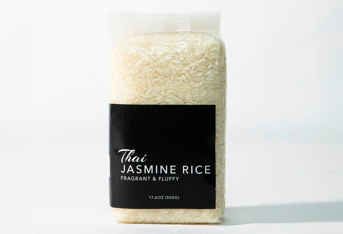 Clear plastic bag filled with long-grain white jasmine rice with black label reading "Thai Jasmine Rice."