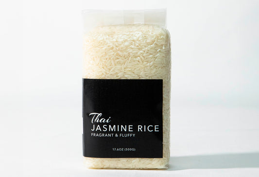 Clear plastic bag filled with long-grain white jasmine rice with black label reading "Thai Jasmine Rice."