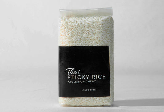 Clear plastic bag containing white sticky rice grains with a black label reading "Thai Sticky Rice, Aromatic & Chewy, 17.6oz 