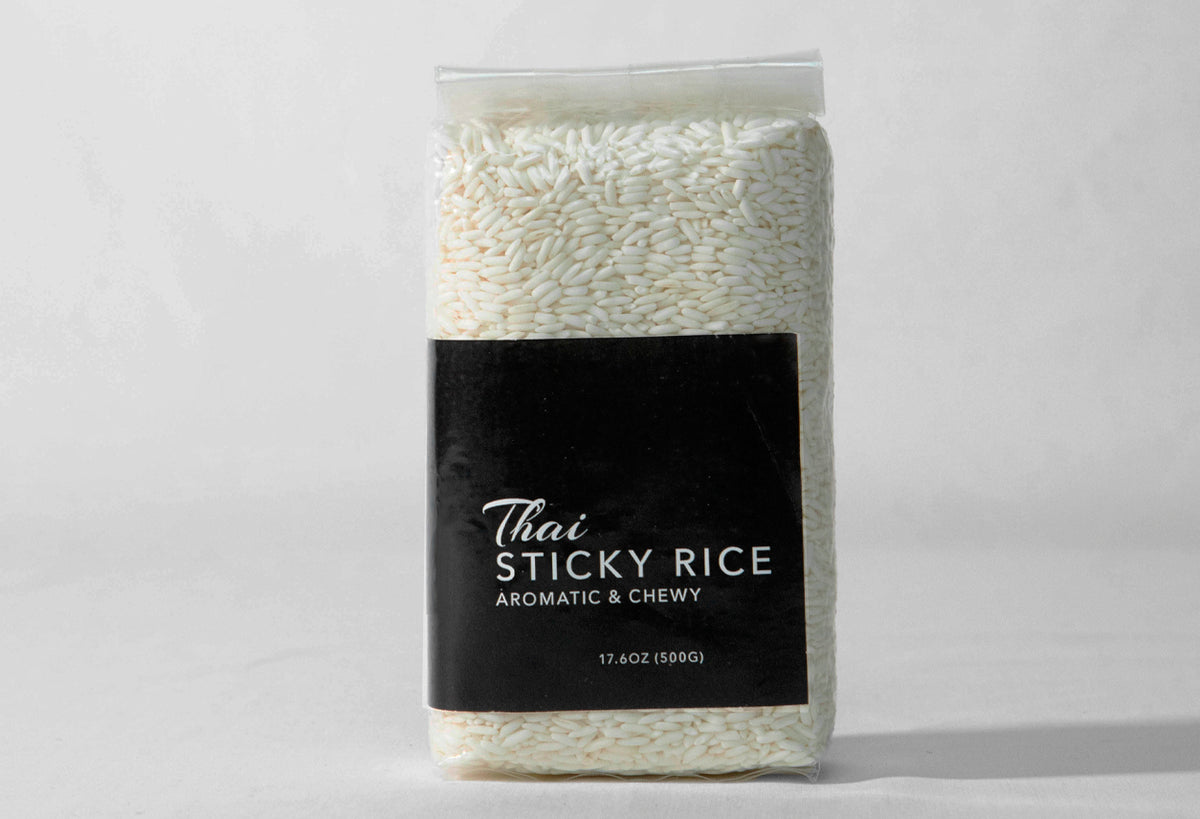 Clear plastic bag containing white sticky rice with black label reading "Thai Sticky Rice, Aromatic & Chewy, 17.6oz (500g)".