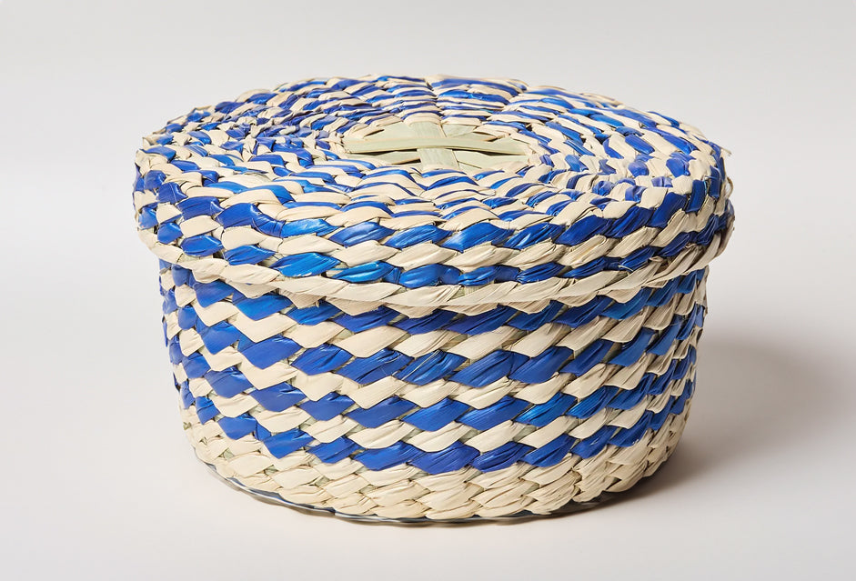 Woven palm basket with blue and cream striped pattern and fitted lid, cylindrical shape.