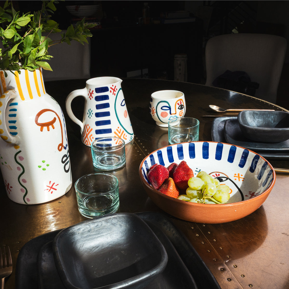 Ceramic bowl with orange exterior and white interior, decorated with blue vertical stripes and multicolored hand-painted face