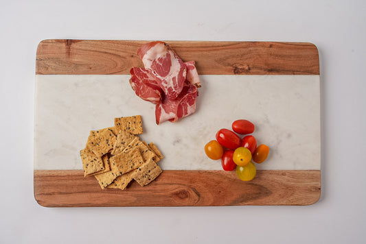 Rectangular serving board with acacia wood edges and white marble center, displaying cured meat, crackers, and cherry tomatoe