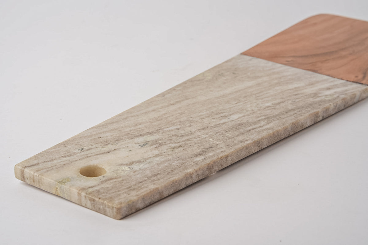 Long rectangular charcuterie board with light marble section and tan acacia wood section, featuring a round handle hole.