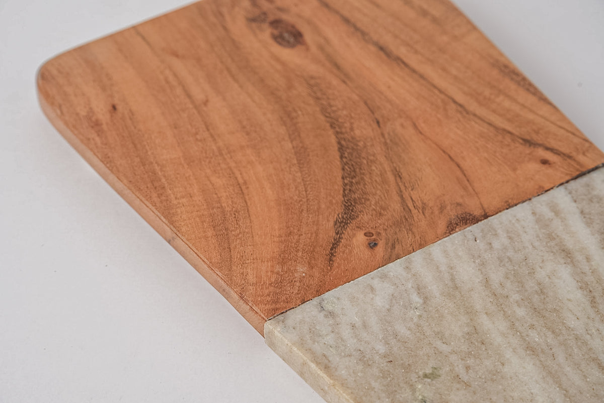 Rectangular charcuterie board with tan acacia wood on one half and light marble on the other half.