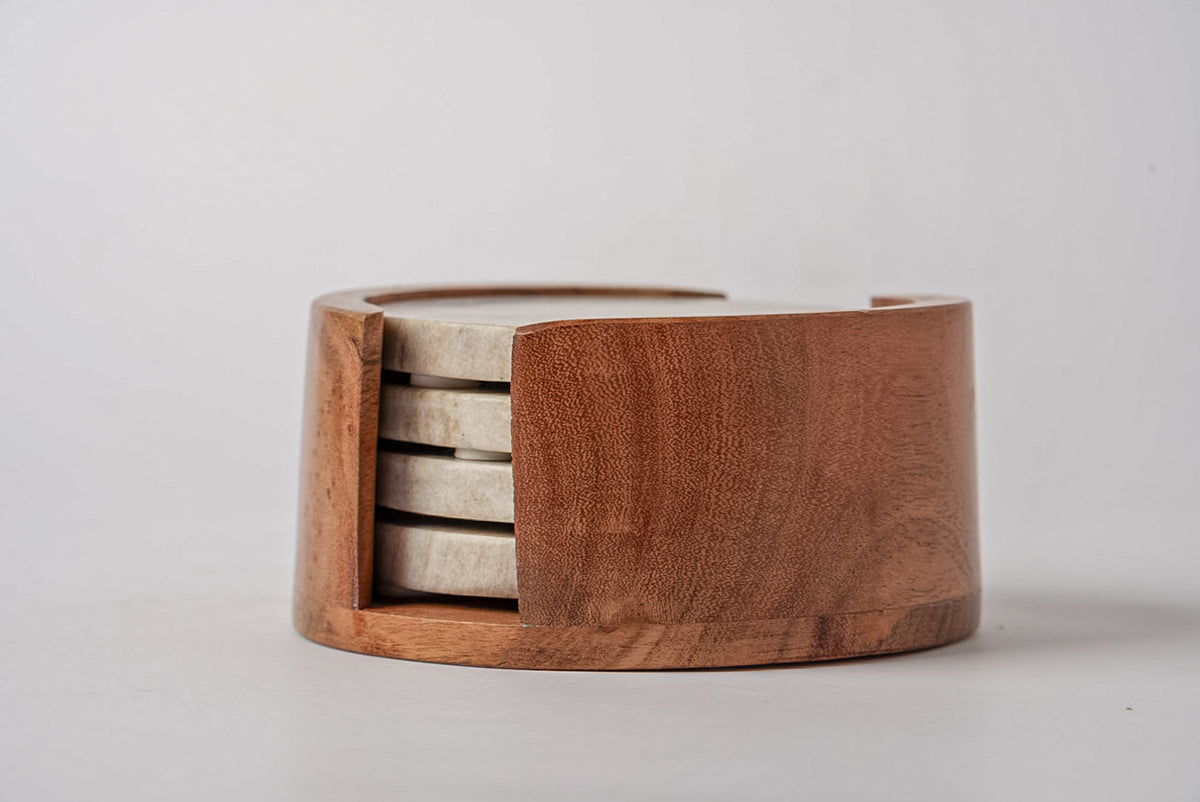 Four tan marble coasters with dark metal bands stored in a wooden holder.