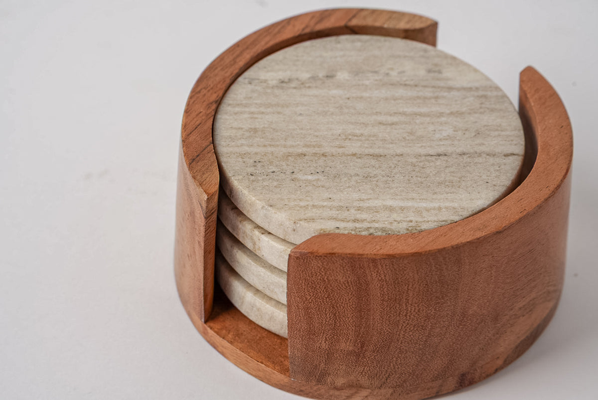 Four tan marble coasters with wood grain pattern stacked in a wooden holder with curved handles.
