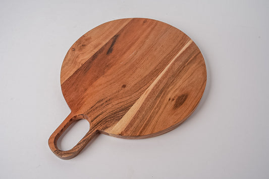 Round wooden serving board with handle in warm brown acacia wood grain.
