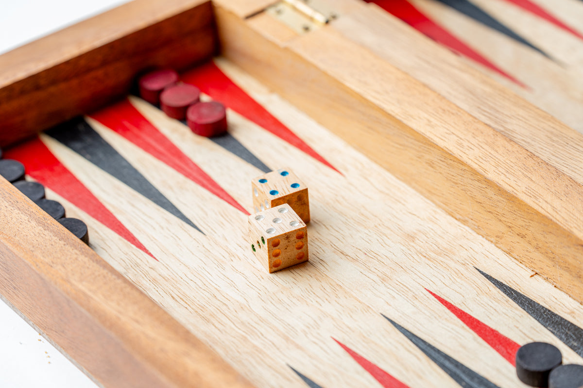 Wooden backgammon board with red, black, and white triangles, dice, and red and black playing pieces.