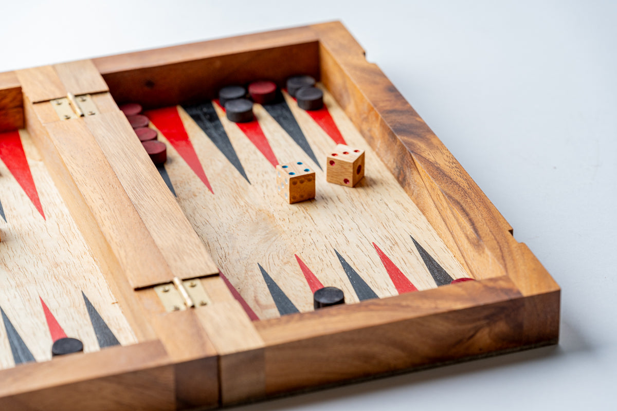Wooden backgammon board with red and black triangles, two dice, and black and red playing pieces.