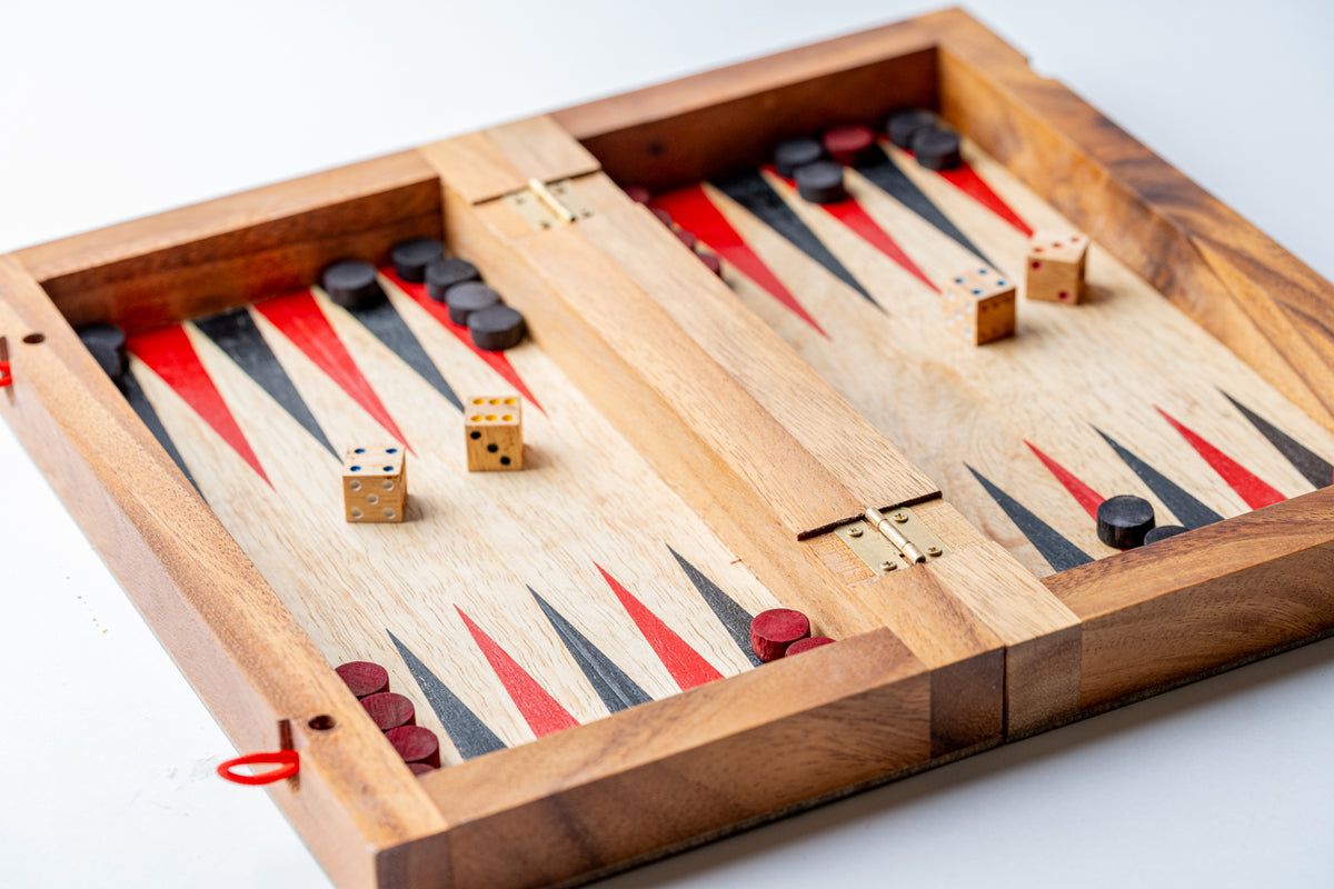 Wooden backgammon board with red and black triangles, wooden dice, and red and black playing pieces.
