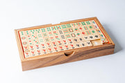 Mahjong game set in wooden box with carved tiles featuring Chinese characters and symbols arranged in rows.