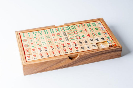 Mahjong game set in wooden box with carved tiles featuring Chinese characters and symbols arranged in rows.