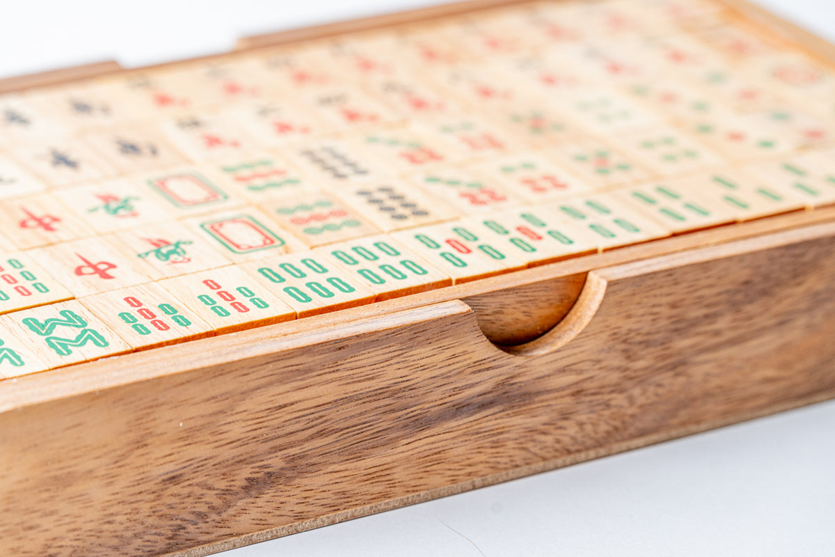 Wooden Mahjong set with carved player rack holding tiles printed with traditional characters and symbols in red, green, and b