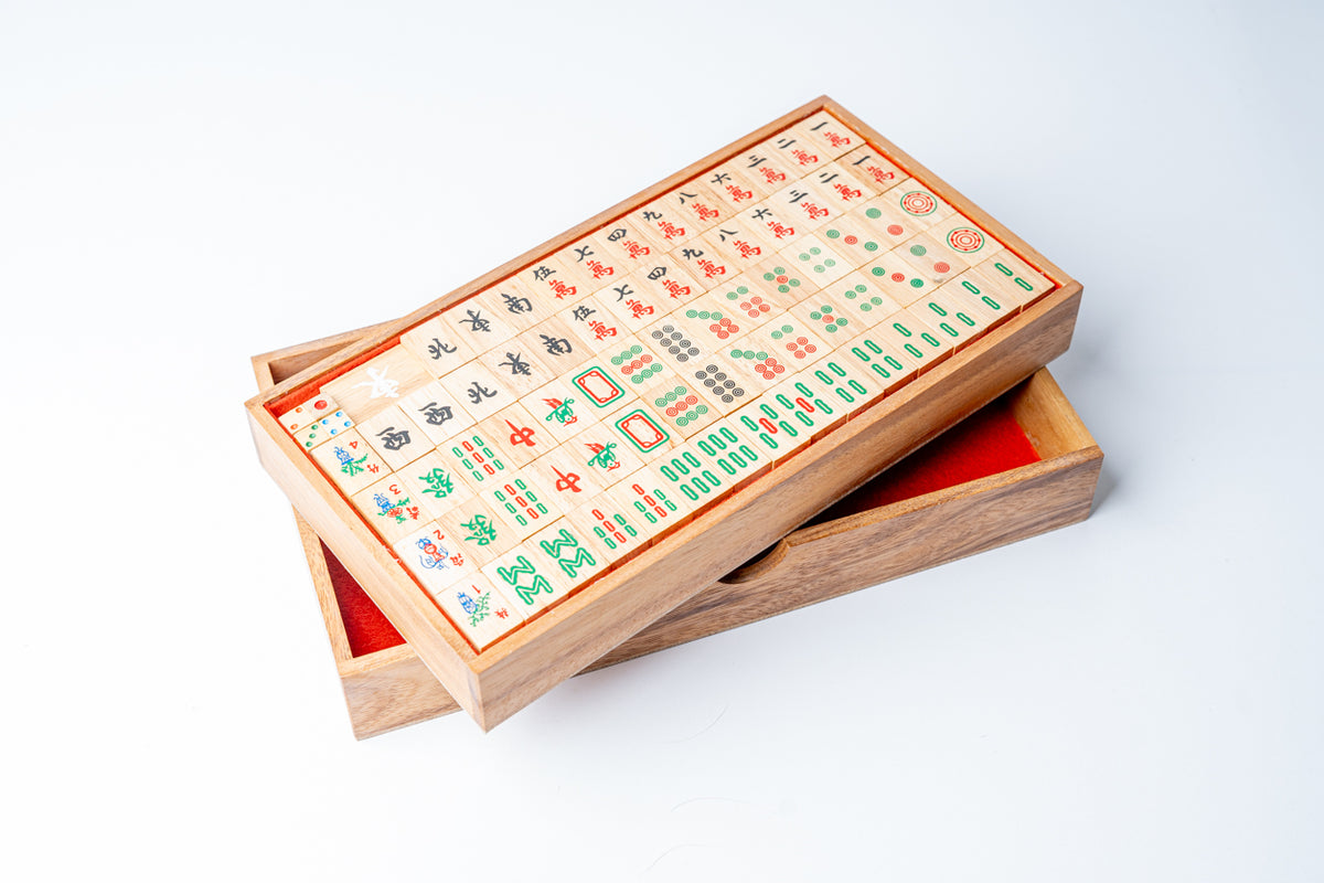 Mahjong set with wooden tiles featuring red, green, and blue characters in wooden box with red storage compartment.