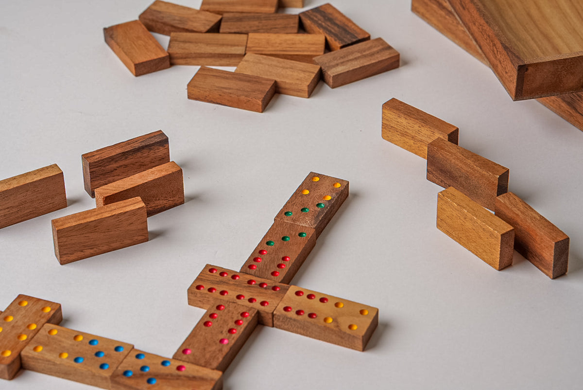 Wooden dominoes set with colored dots arranged in a game layout, including plain tiles and a storage box.