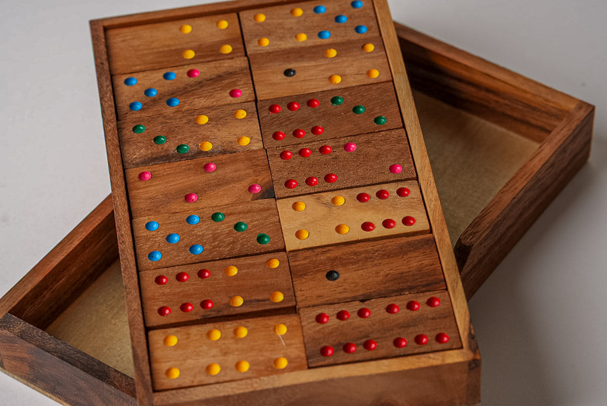 Wooden domino set with colored dots in a mangowood box, showing multiple tiles with various color combinations.
