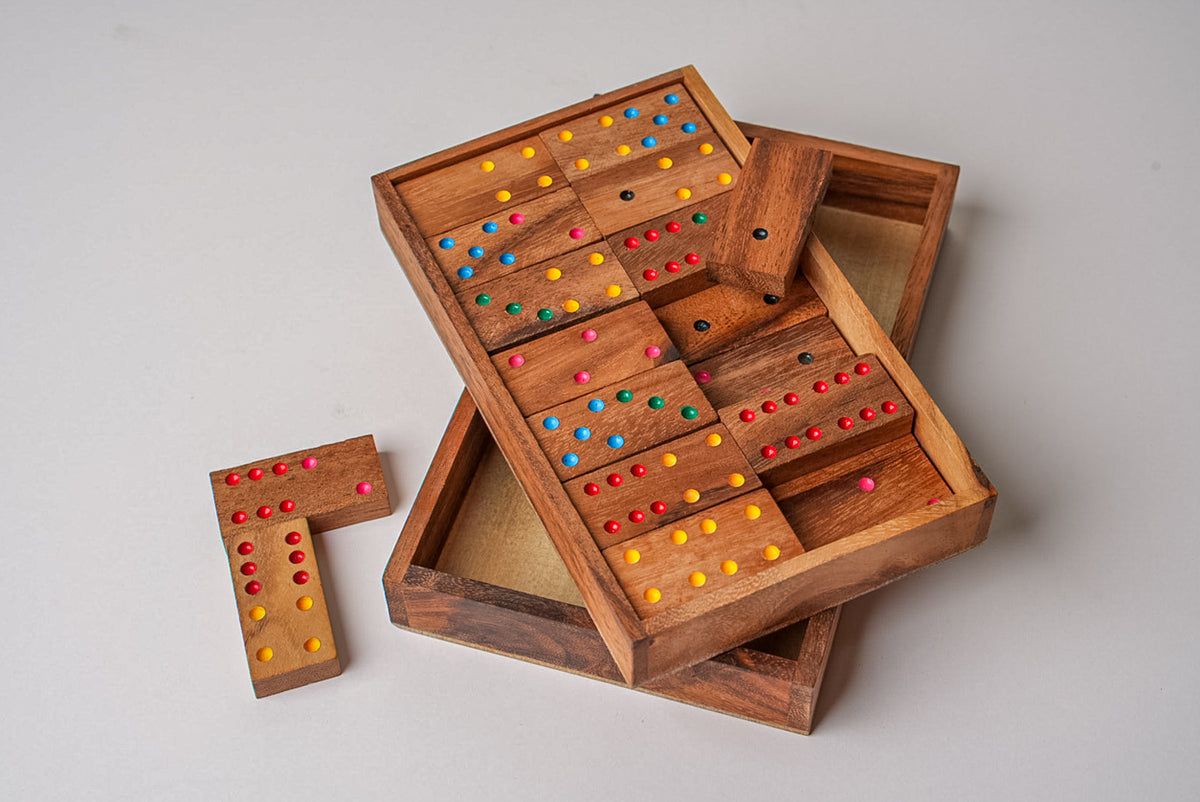 Wooden domino set with colorful dot pips in wooden storage box with open lid and compartments.