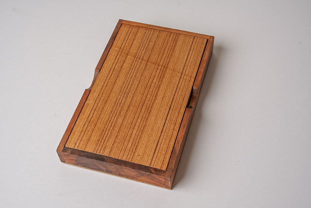 Wooden domino set box with light wood top and darker wood frame, closed lid with grain texture visible.