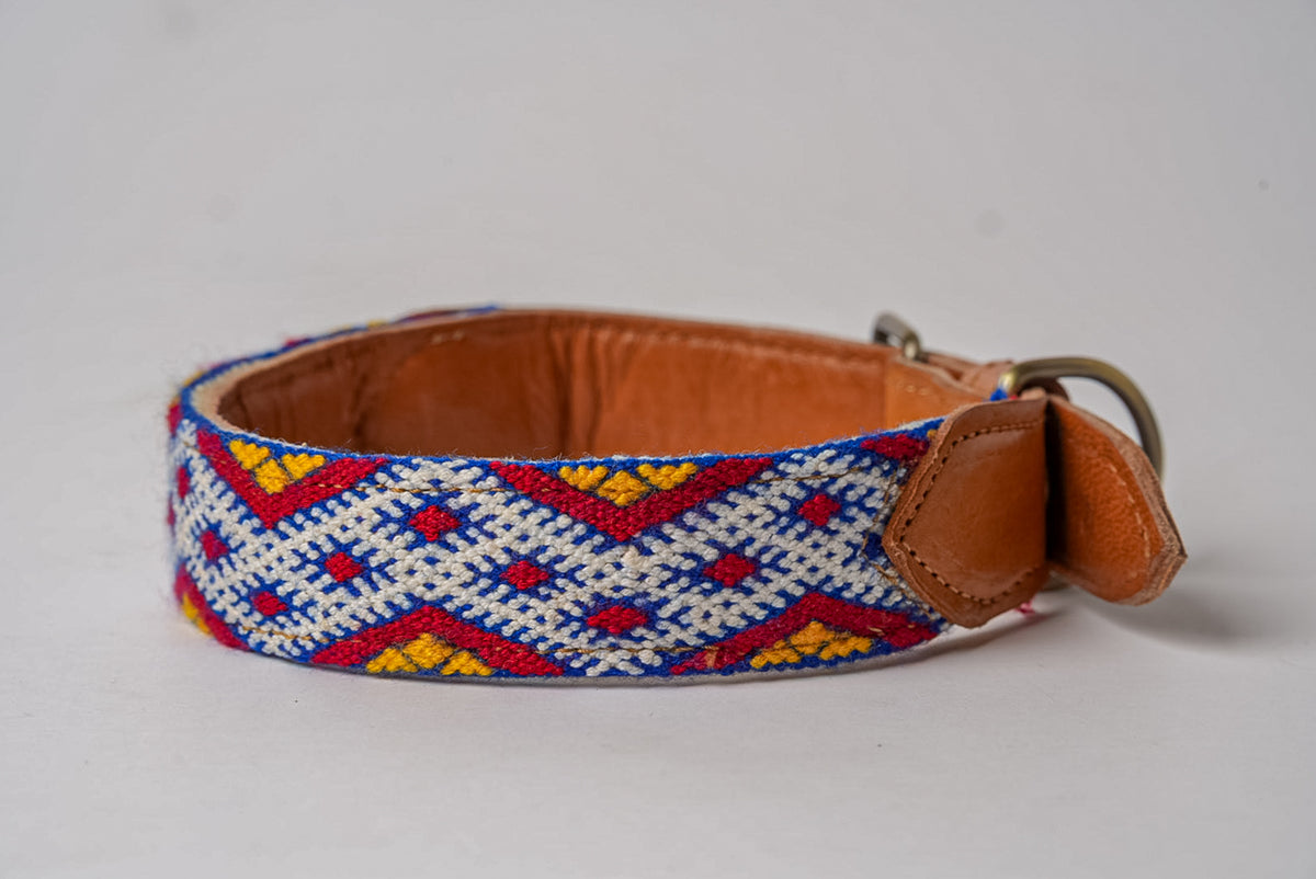 Woven collar with geometric diamond pattern in red, blue, yellow, and cream with tan leather trim and metal buckle.