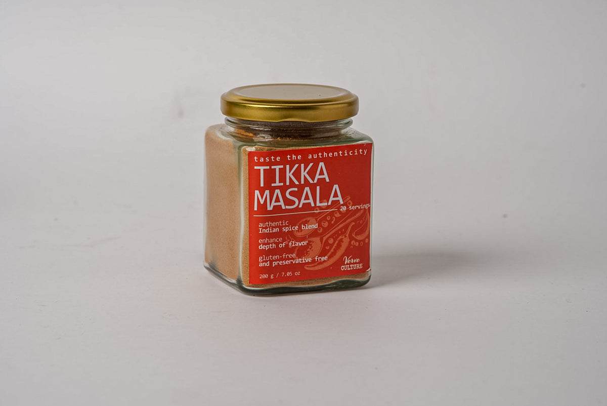 Glass jar with gold lid containing tan spice blend and red label reading "Tikka Masala."