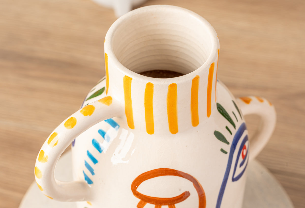 Cream ceramic vase with yellow vertical stripes, blue and orange geometric patterns, and two handles.