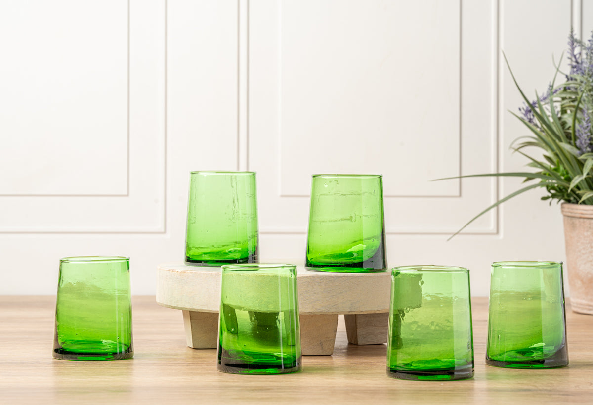 Six green cone-shaped glasses with textured surfaces arranged on wooden blocks.