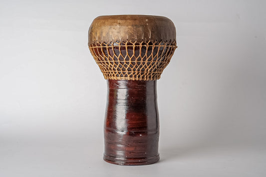 Wooden darbouka drum with carved geometric pattern on upper section and dark red-brown finish on cylindrical body.