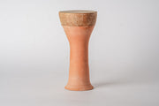 Terracotta goblet-shaped drum with narrow cylindrical body, wider top rim, and textured brown surface.