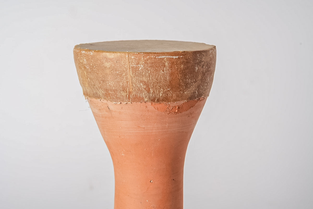 Terracotta drum with wide rounded body tapering to narrow neck and flat membrane top.