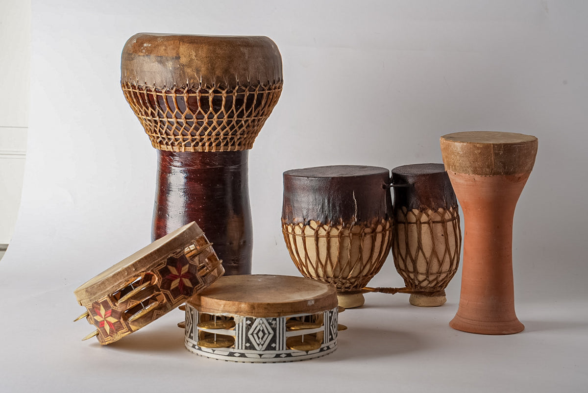 Collection of five wooden drums with rope tuning and varied sizes, including goblet and cylindrical shapes in natural wood an