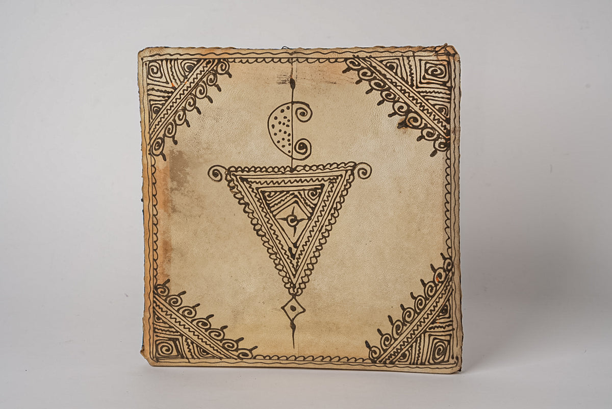 Square Moroccan drum with natural leather surface featuring geometric and ornamental line designs in brown ink.