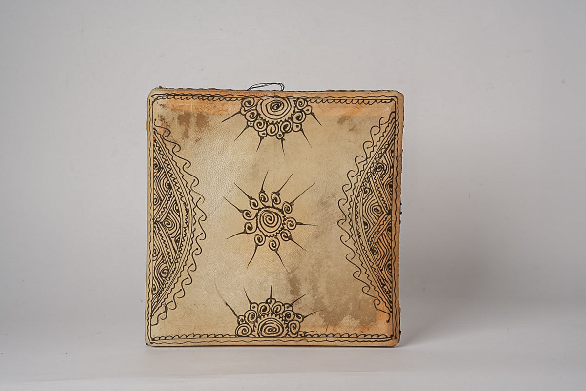 Square frame drum with natural leather head decorated with geometric and sun motif patterns burned into the surface.