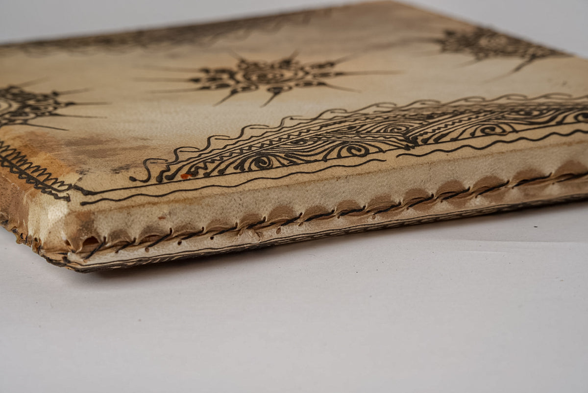 Square drum with natural skin head featuring burnt geometric and floral designs along edges and surface.