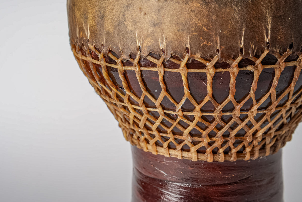 Goblet drum with rope tuning, tan leather head, and dark wooden body.